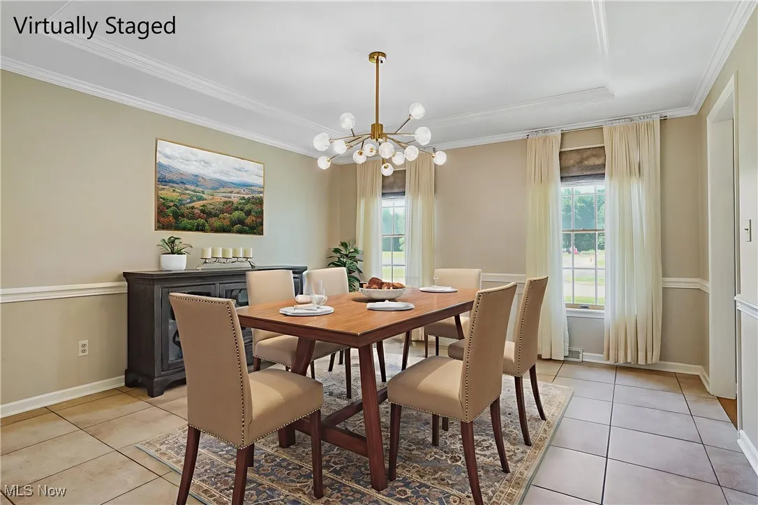 Dining space with ornamental molding, a chandelier, and light tile patterned flooring