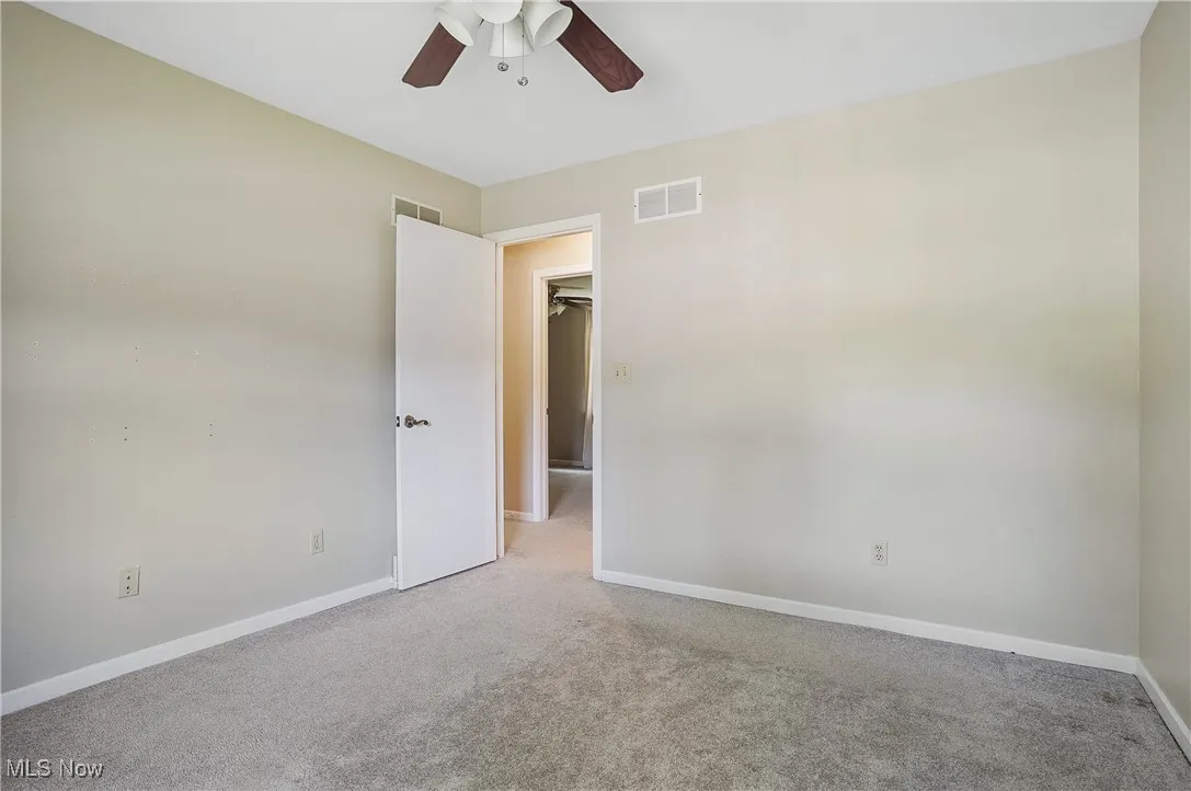 Carpeted spare room featuring ceiling fan and baseboards