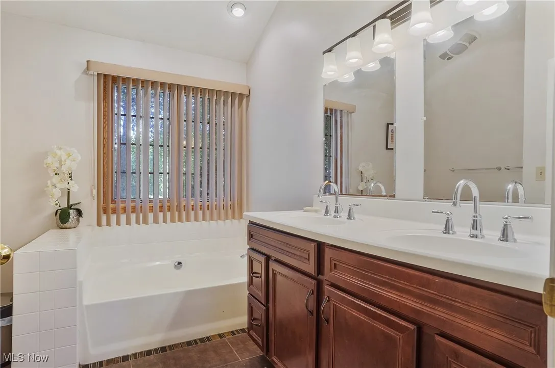 Bathroom with double vanity, a bath, and tile patterned floors