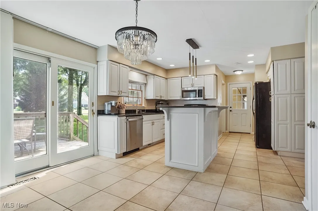 Kitchen with dark countertops, light tile patterned floors, white cabinetry, a chandelier, and recessed lighting