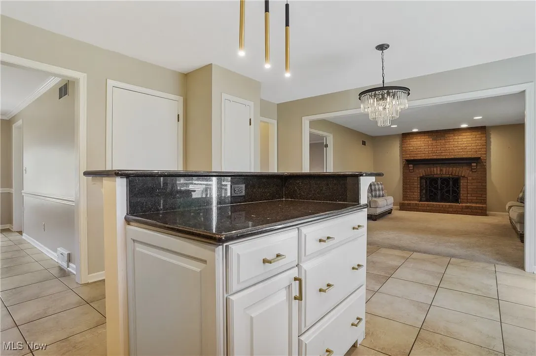 Kitchen featuring light tile patterned floors, light carpet, open floor plan, pendant lighting, and ornamental molding