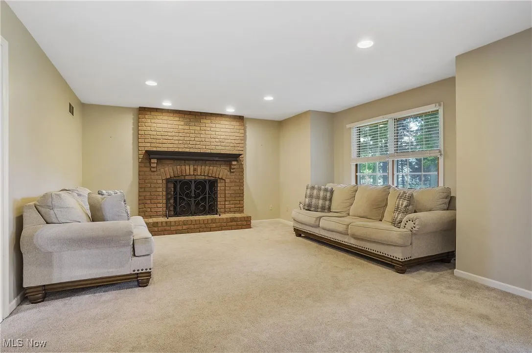 Living room with carpet floors, recessed lighting, and a brick fireplace
