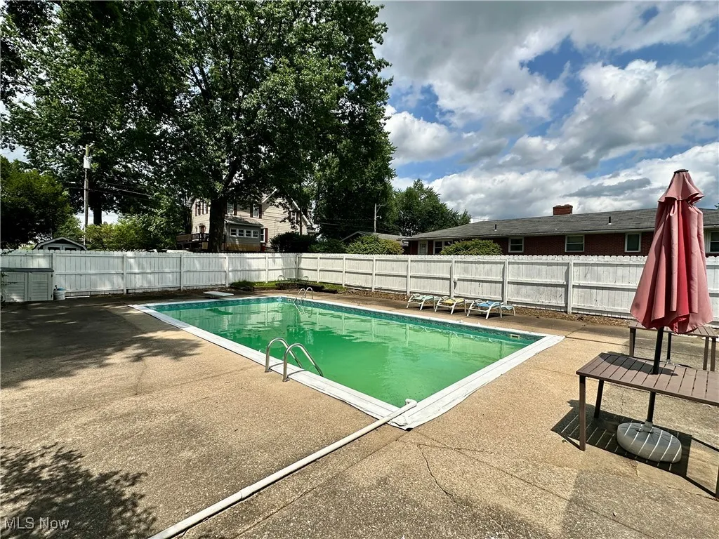 View of swimming pool with a full surround patio and a diving board