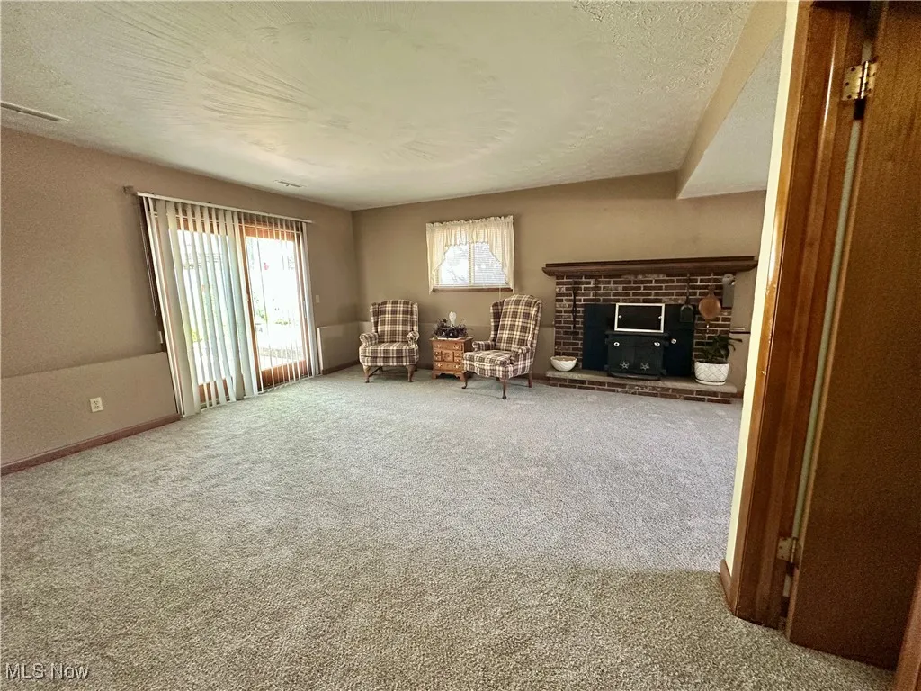 Lower level family room with a brick fireplace and sliding door to access patio, backyard and pool