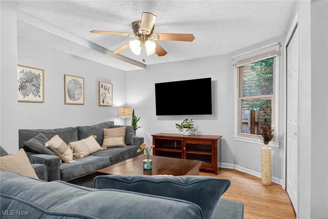 Living area featuring light wood-style floors, a textured ceiling, and ceiling fan
