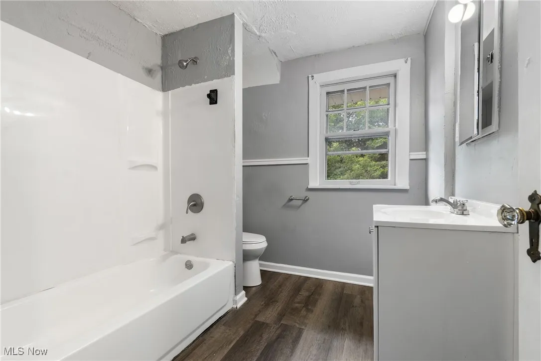 Full bathroom featuring wood finished floors, vanity,  shower combination, and a textured ceiling