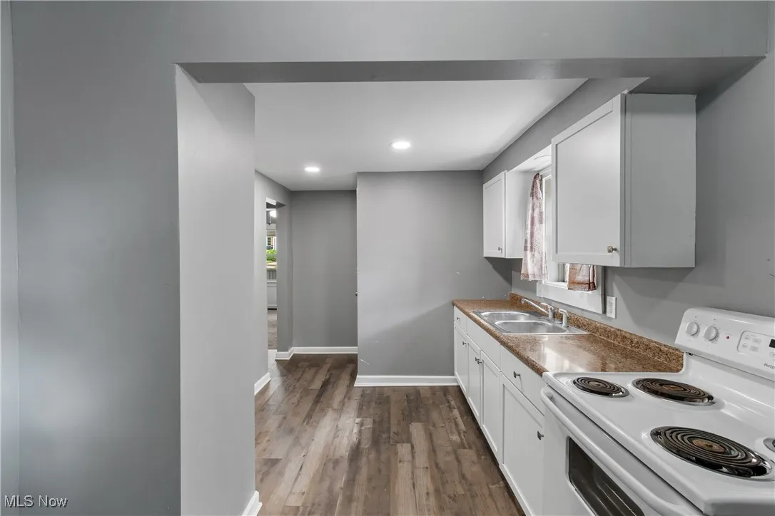 Kitchen with electric range, white cabinetry, dark wood-style floors, and recessed lighting