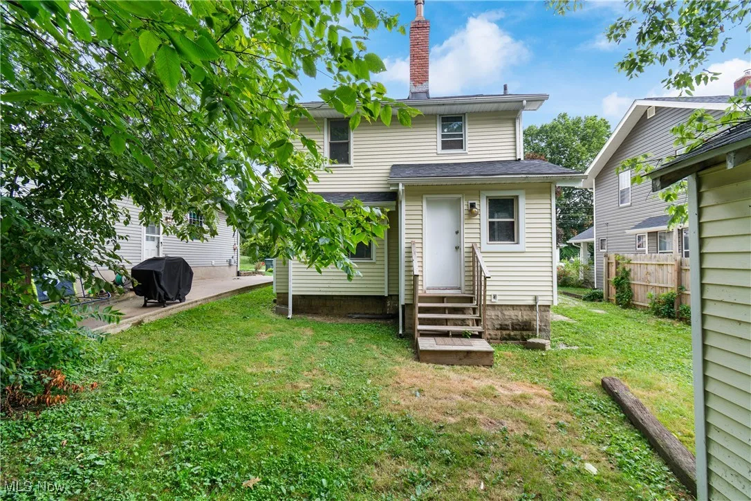 Back of property with entry steps, a chimney, and a patio area