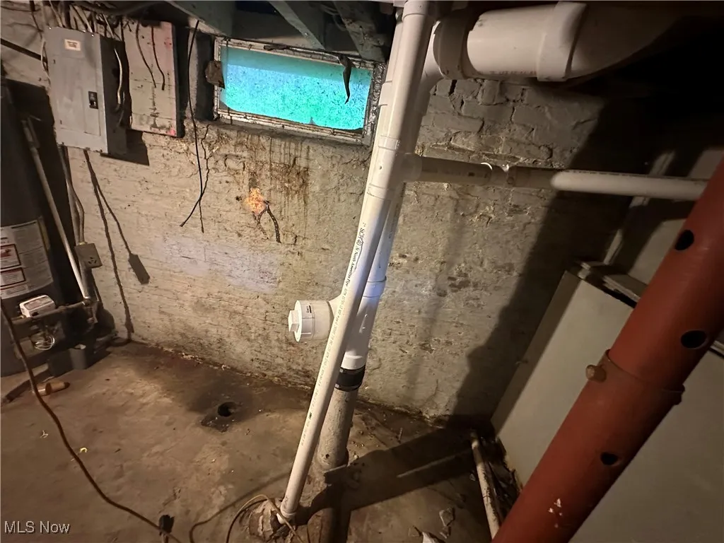 Unfinished below grade area with electric panel and water heater