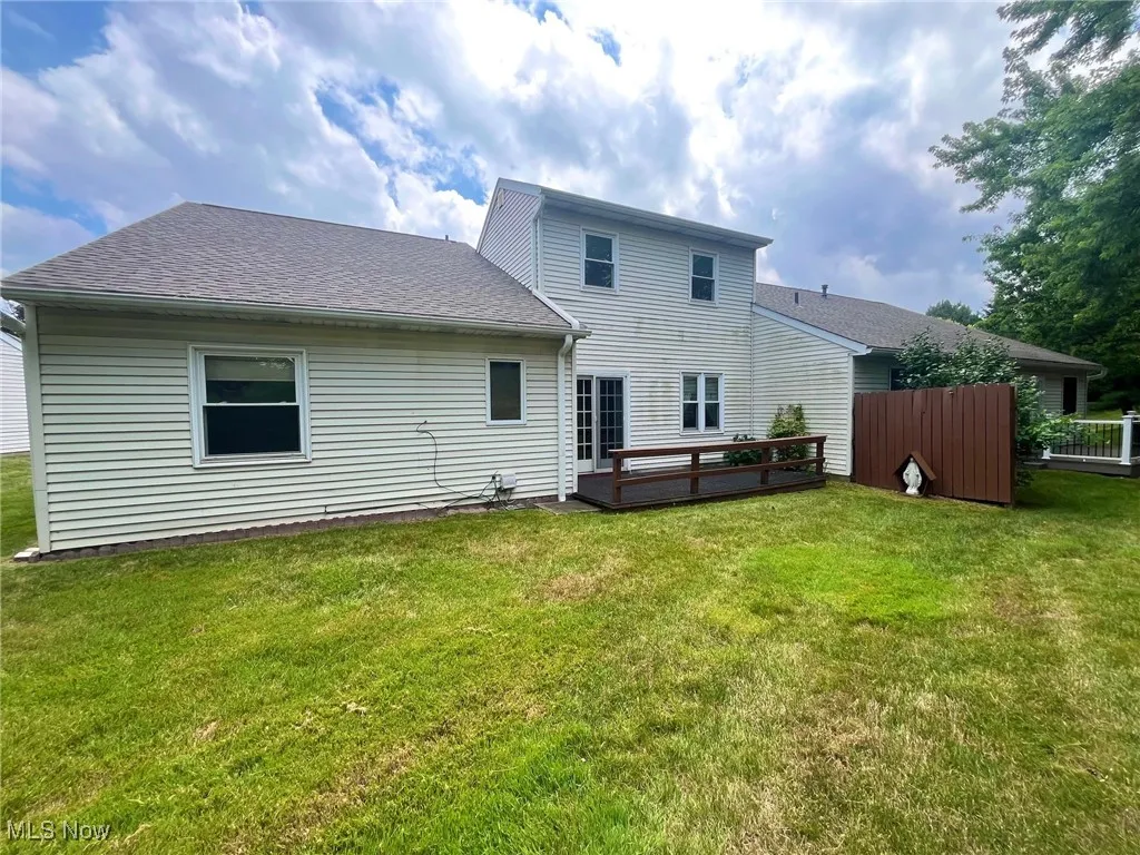 Back of property with roof with shingles and a lawn