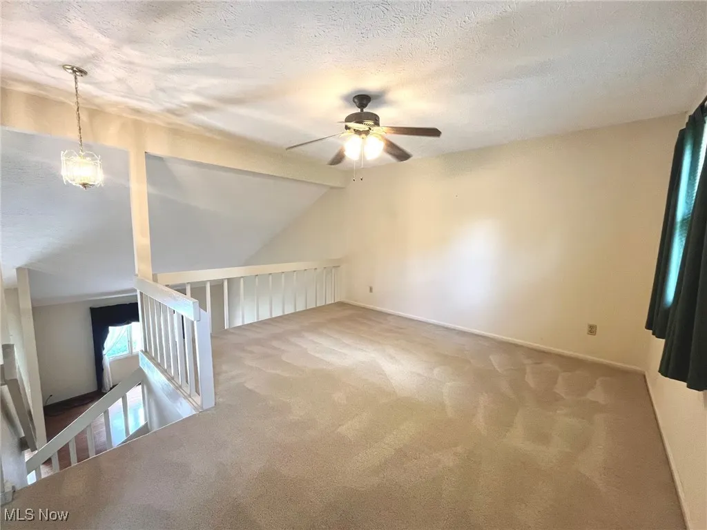 carpeted loft with ceiling fan