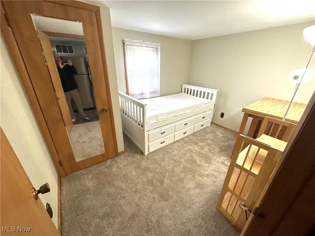 Bedroom featuring carpet flooring and freestanding refrigerator