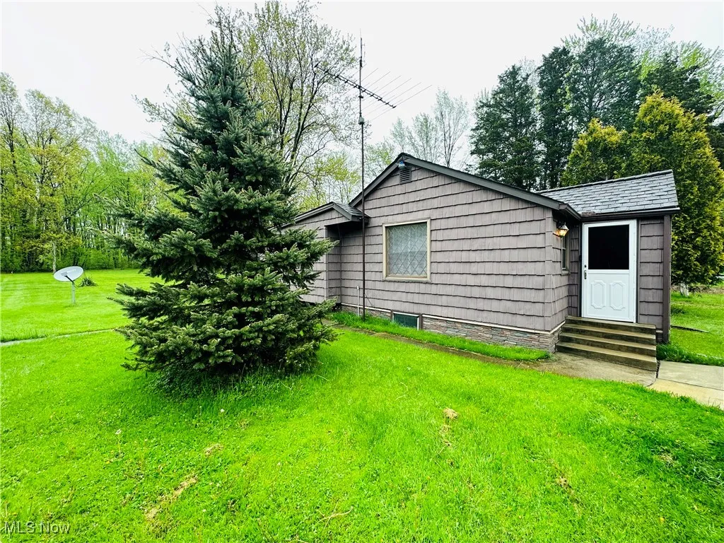 View of home's exterior with a yard and entry steps