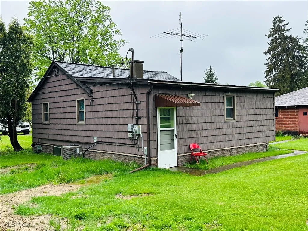 Rear view of house featuring a chimney and a yard