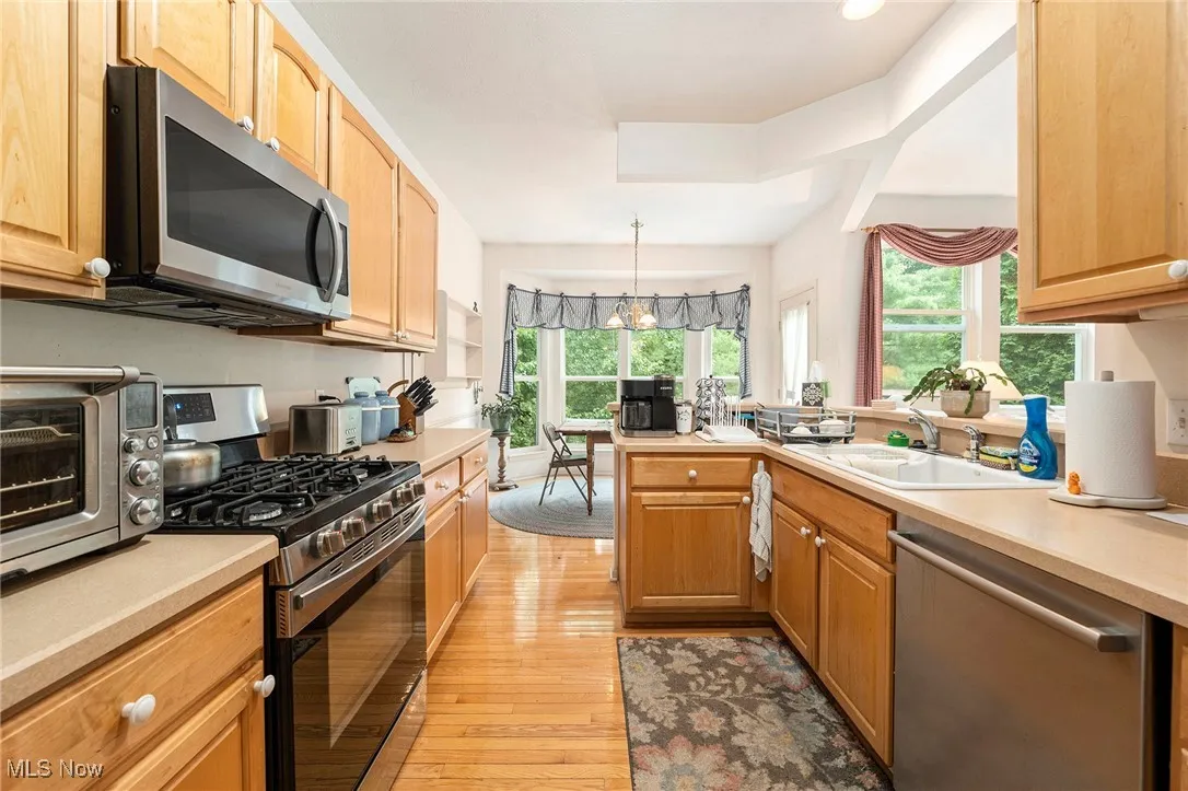 Kitchen with stainless steel appliances, light wood-style floors, plenty of natural light, and light countertops