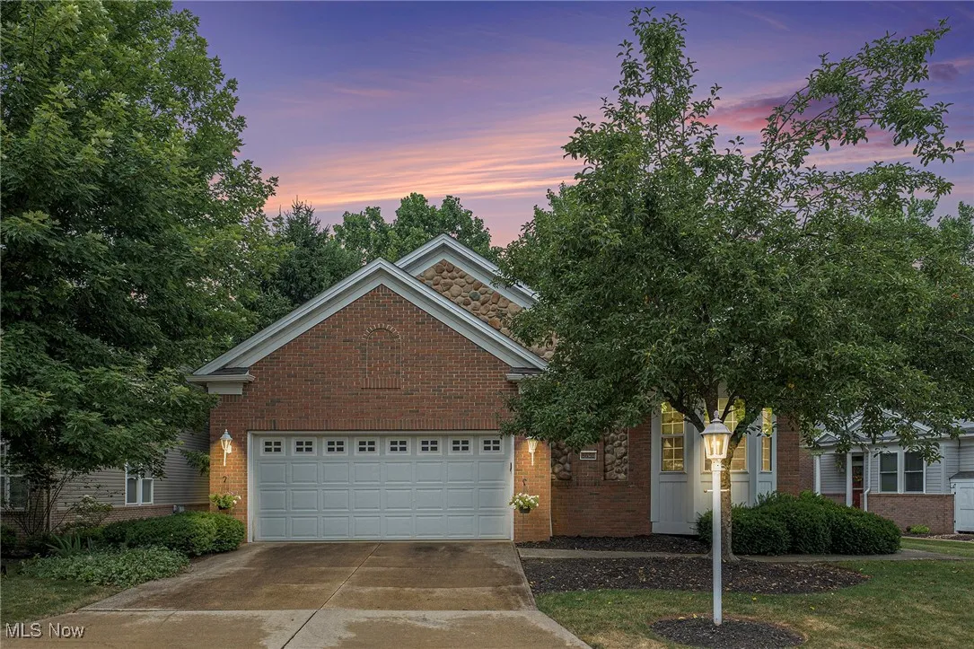 View of front facade featuring driveway, brick siding, and an attached garage