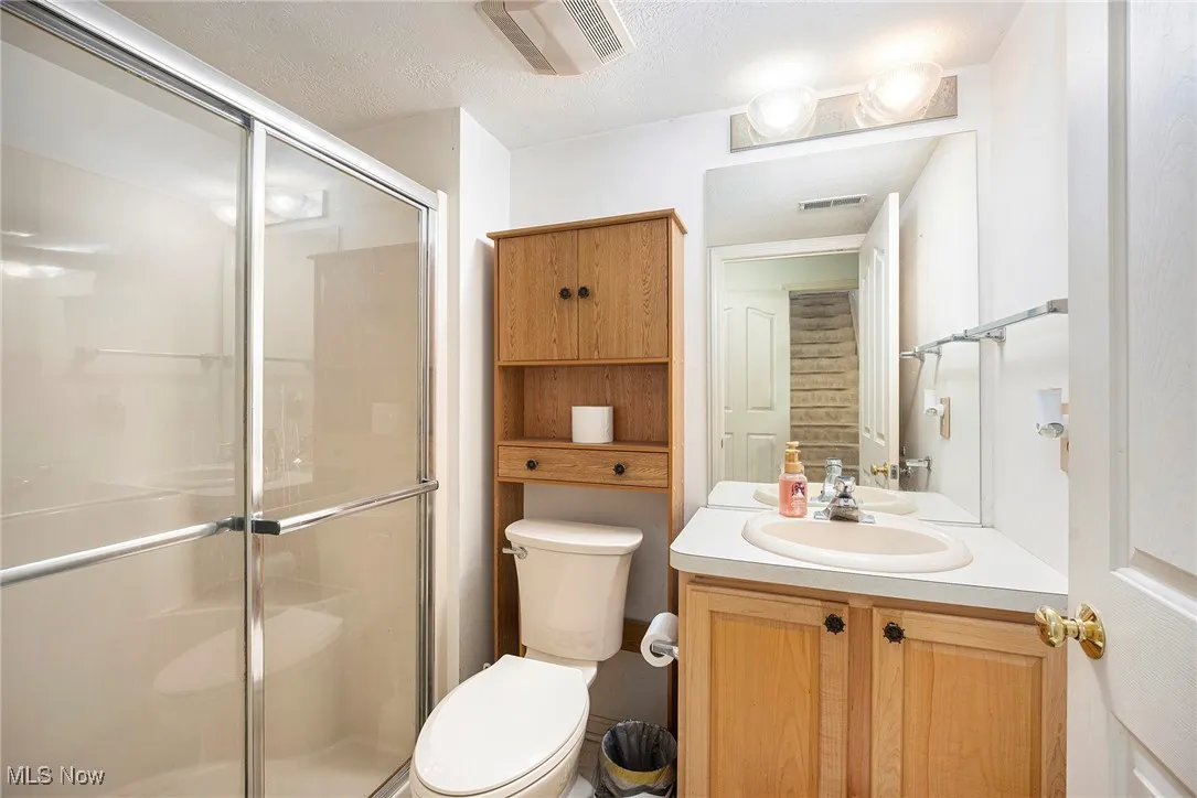 Full bathroom with vanity, a shower stall, and a textured ceiling