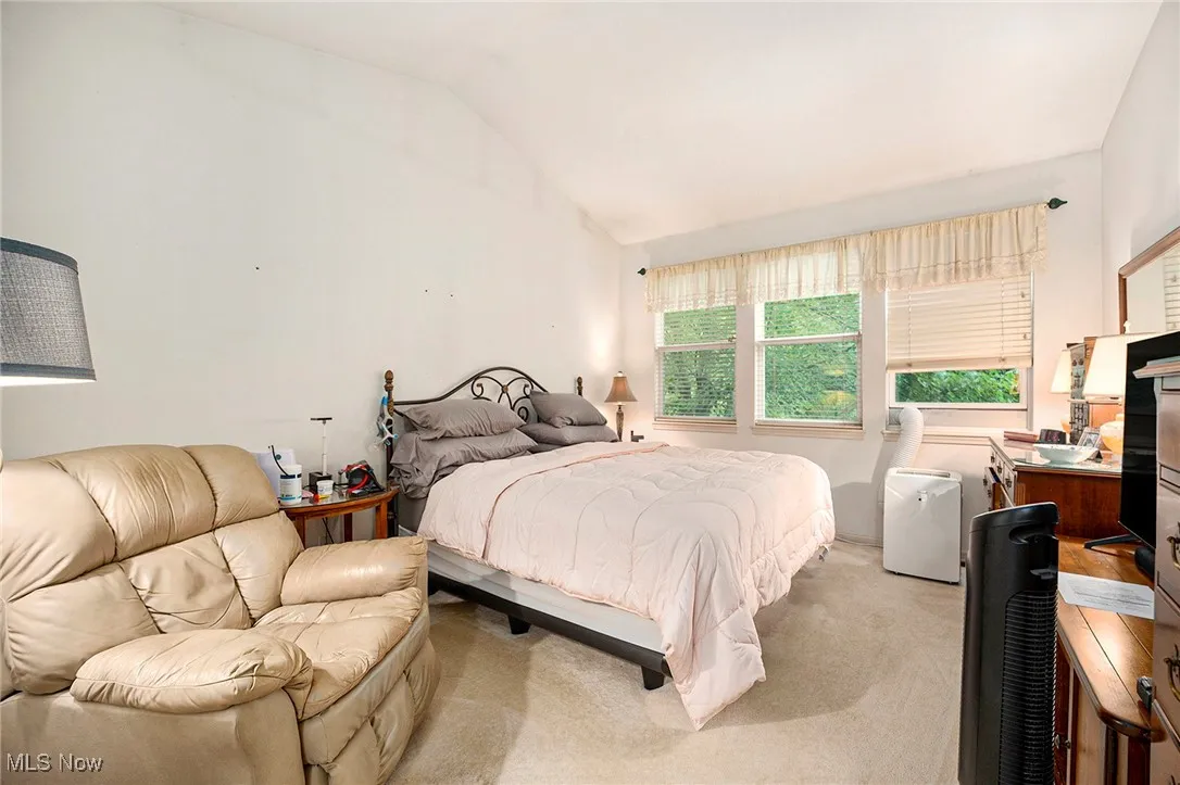 Bedroom featuring vaulted ceiling, light carpet, and an office area