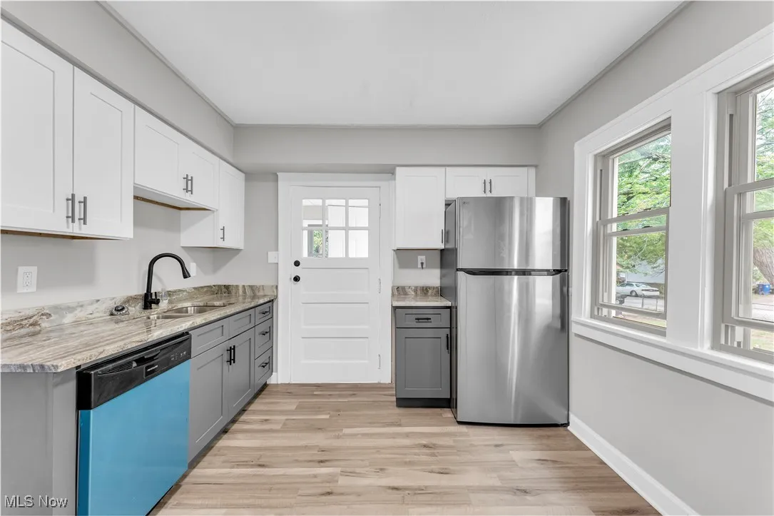 Kitchen featuring freestanding refrigerator, dishwasher, light wood-style floors, and healthy amount of natural light