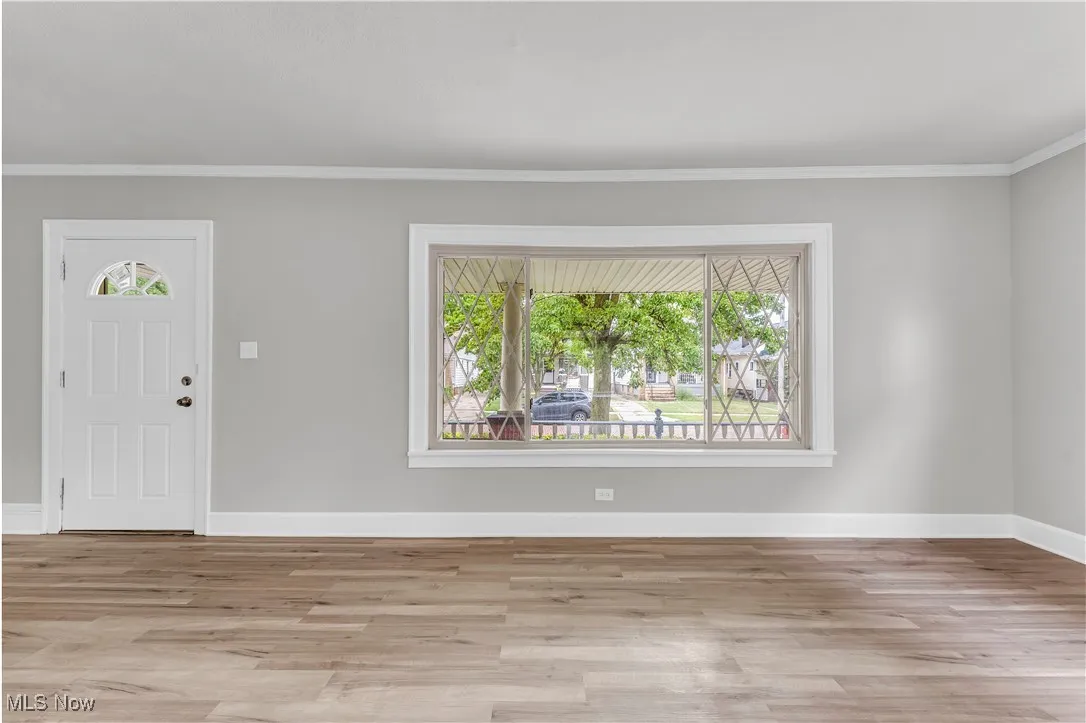 Foyer entrance with healthy amount of natural light, wood finished floors, and ornamental molding