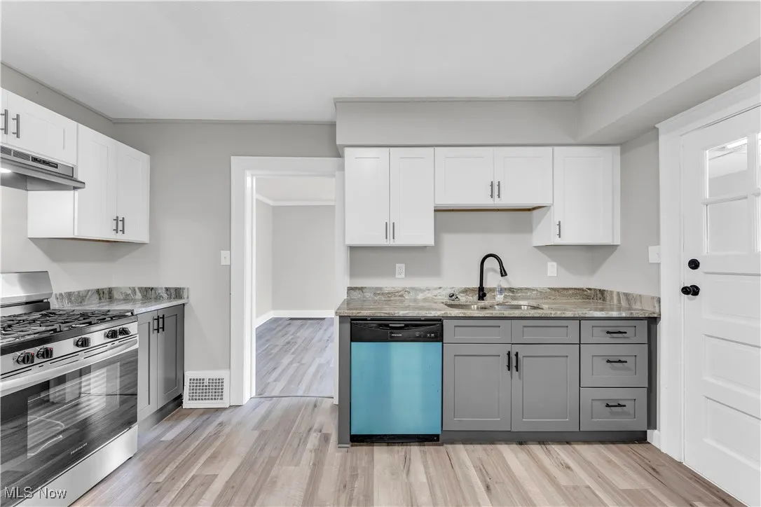 Kitchen featuring gas stove, dishwasher, gray cabinetry, light wood-style floors, and under cabinet range hood