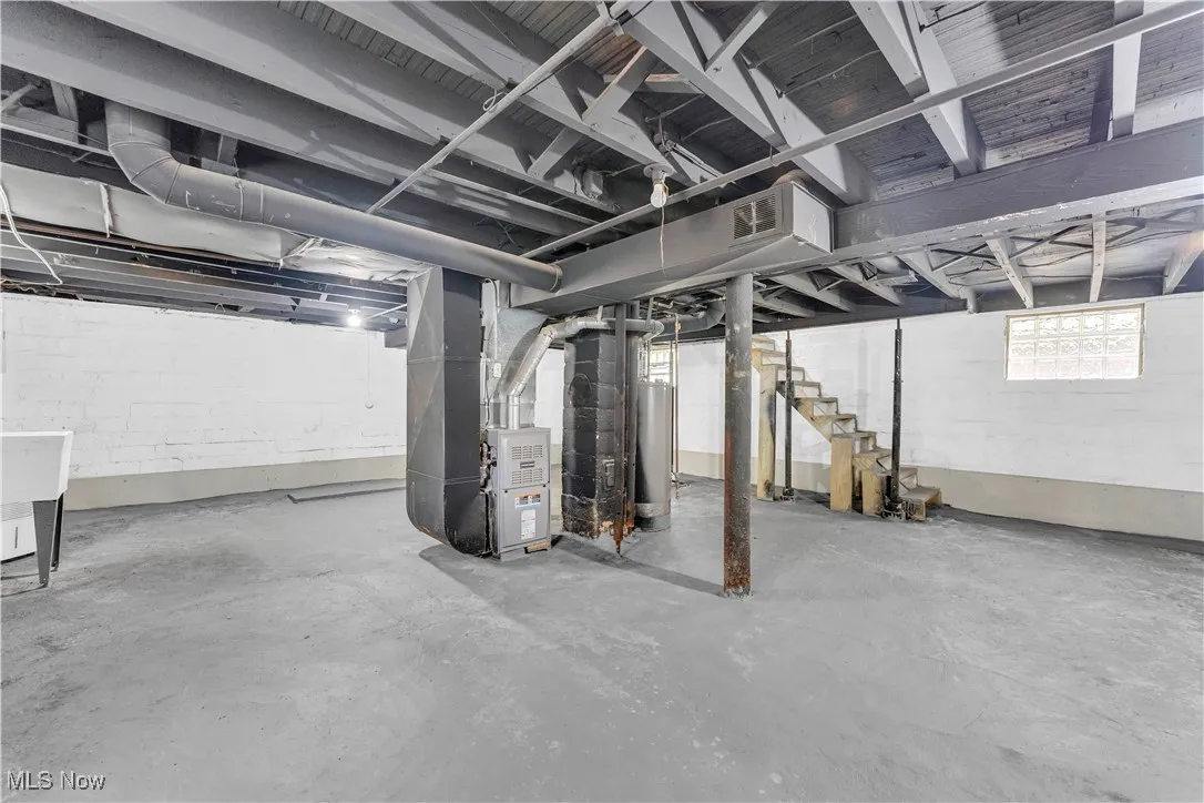 Below grade area with heating unit, stairs, and gas water heater