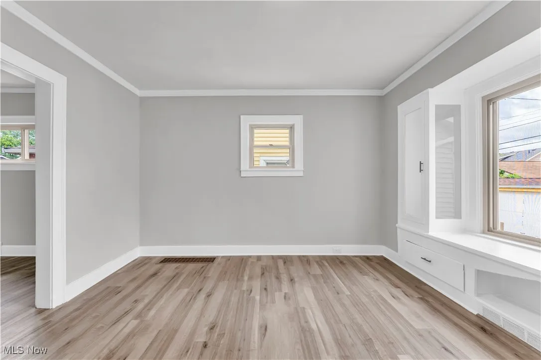 Unfurnished room featuring crown molding and light wood-style floors