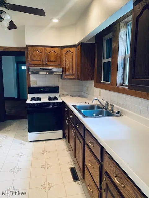 Kitchen with gas stove, light countertops, a ceiling fan, tasteful backsplash, and recessed lighting