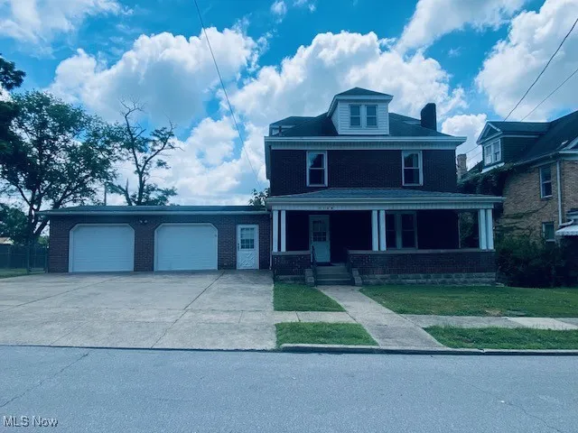 Traditional style home featuring driveway, an attached garage, a porch, and brick siding