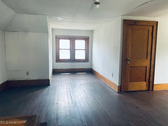 Bonus room with dark wood-style flooring and baseboards