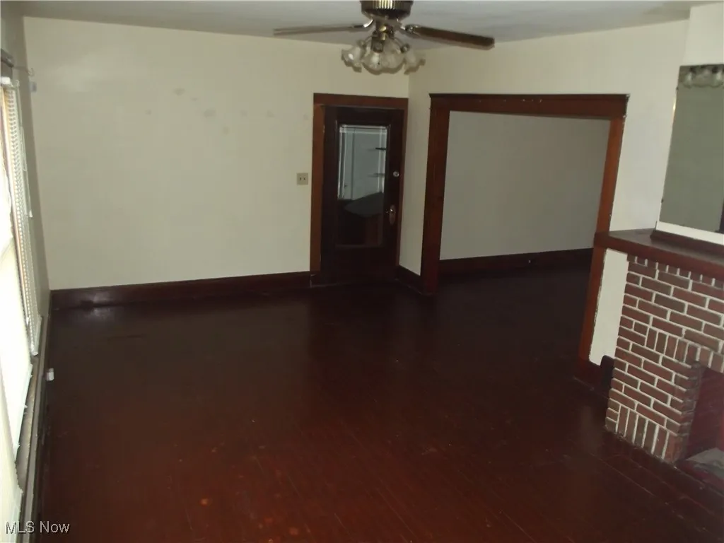 Empty room with dark hardwood / wood-style flooring and ceiling fan