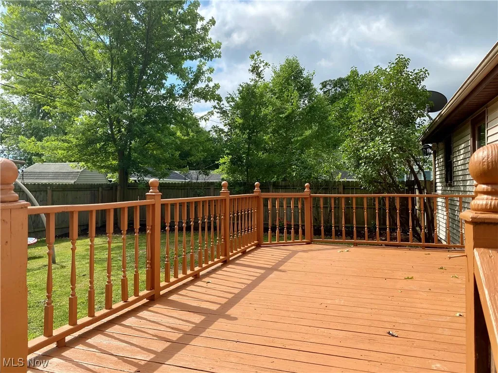 Wooden terrace with a fenced backyard