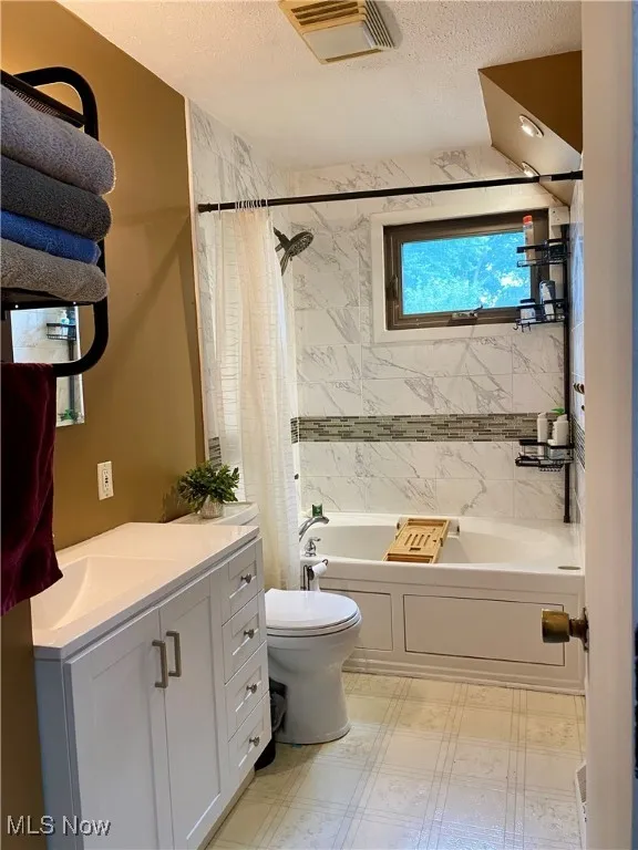 Full bath featuring a textured ceiling, vanity, shower / bath combination with curtain, and tile patterned floors