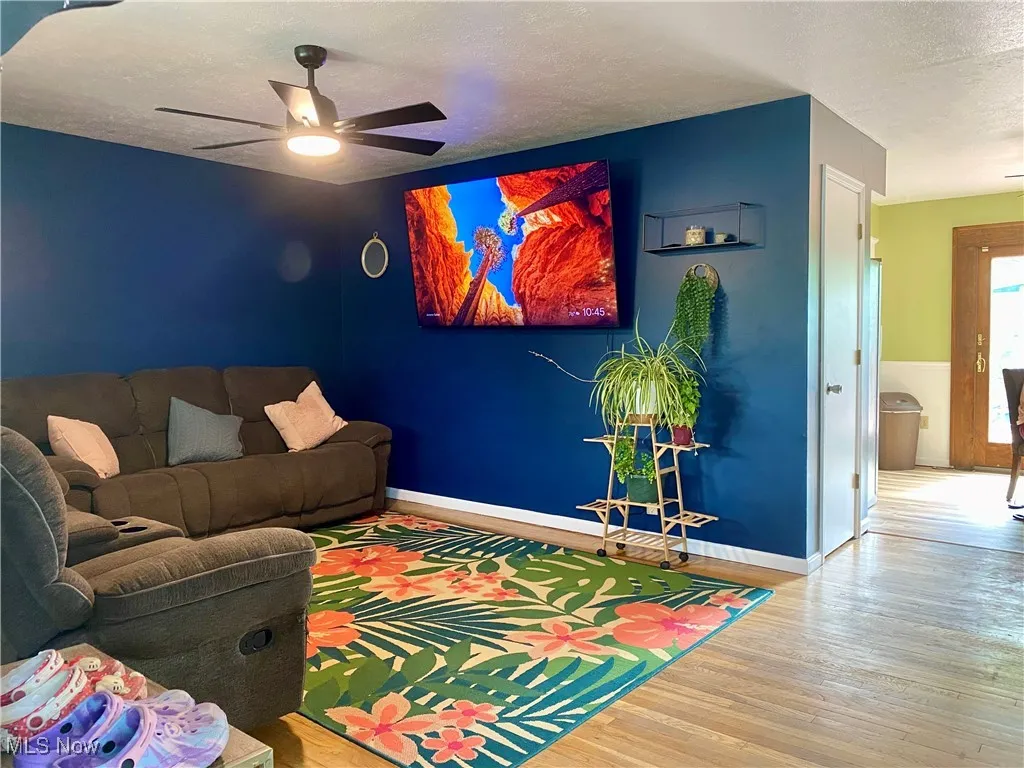 Living room with wood finished floors, a textured ceiling, and a ceiling fan