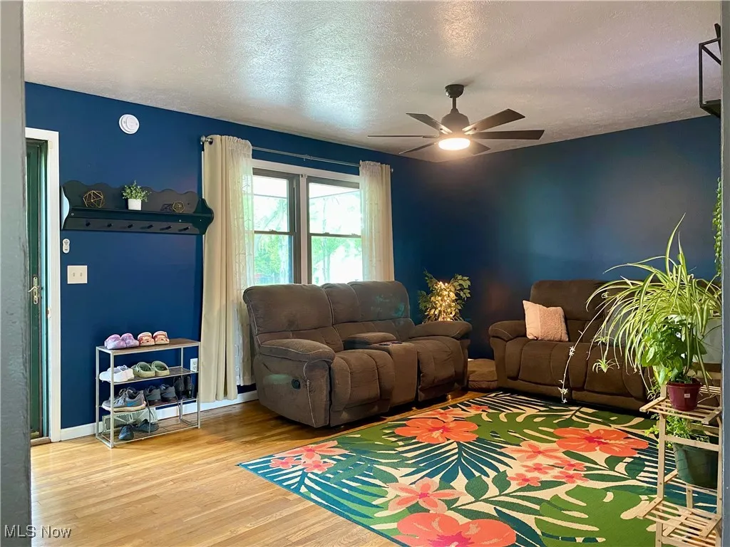 Living room with wood finished floors, a ceiling fan, and a textured ceiling
