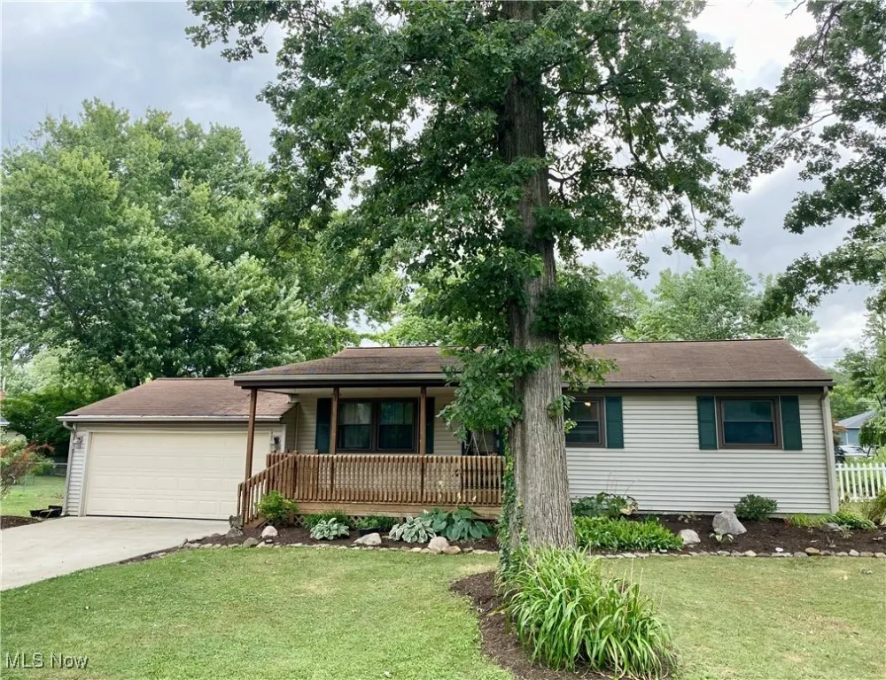 Ranch-style house with covered porch, concrete driveway, a front yard, and a garage