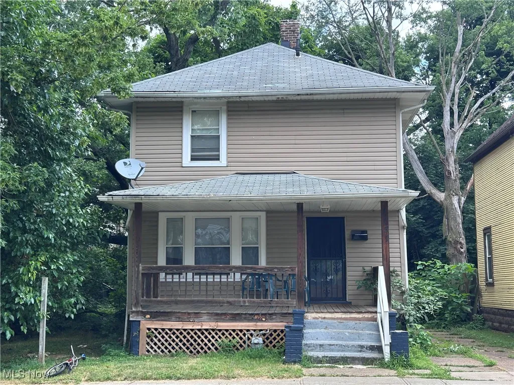 American foursquare style home featuring a porch and a chimney