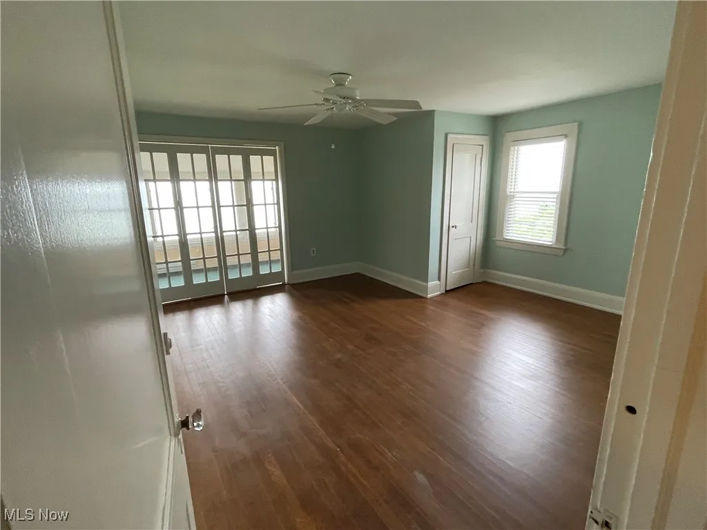 Unfurnished room featuring dark wood-style flooring and ceiling fan