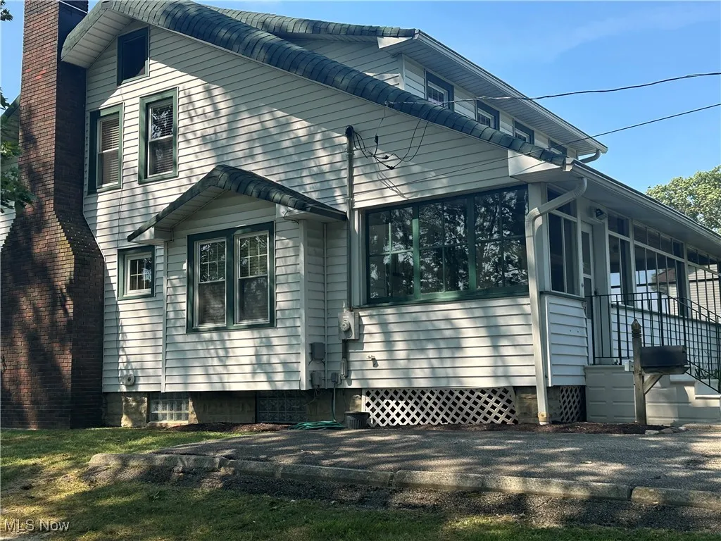 View of side of home with a chimney and a sunroom