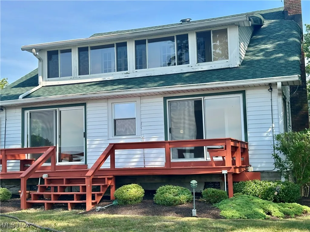 Rear view of property with roof with shingles, a chimney, and a deck