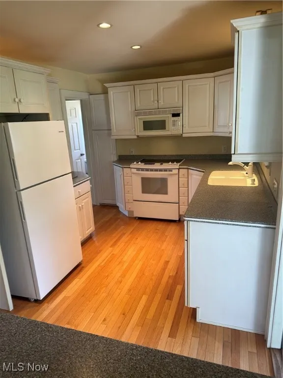 Kitchen with refrigerator, white electric stove, dark countertops, recessed lighting, and light wood-style flooring