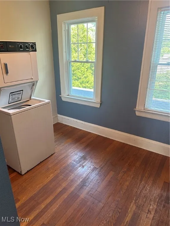 Laundry area featuring hardwood / wood-style flooring, plenty of natural light, and stacked washing machine and dryer