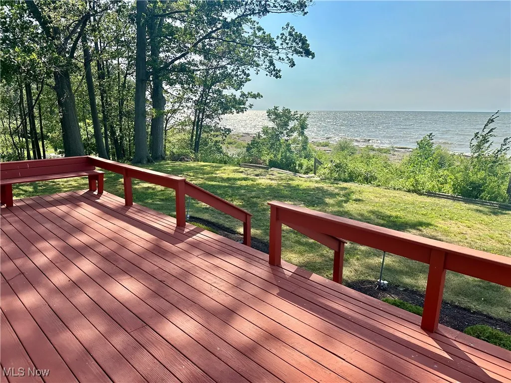 Deck with a water view and a lawn