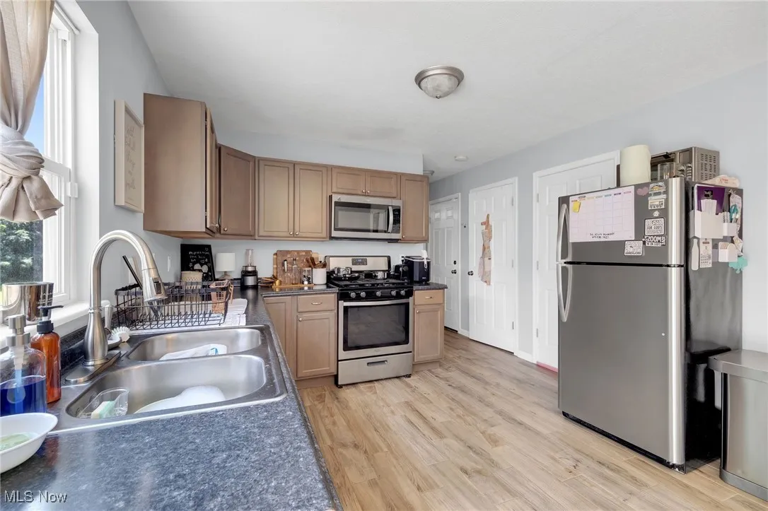 Kitchen featuring stainless steel appliances, light wood-style flooring, and dark countertops