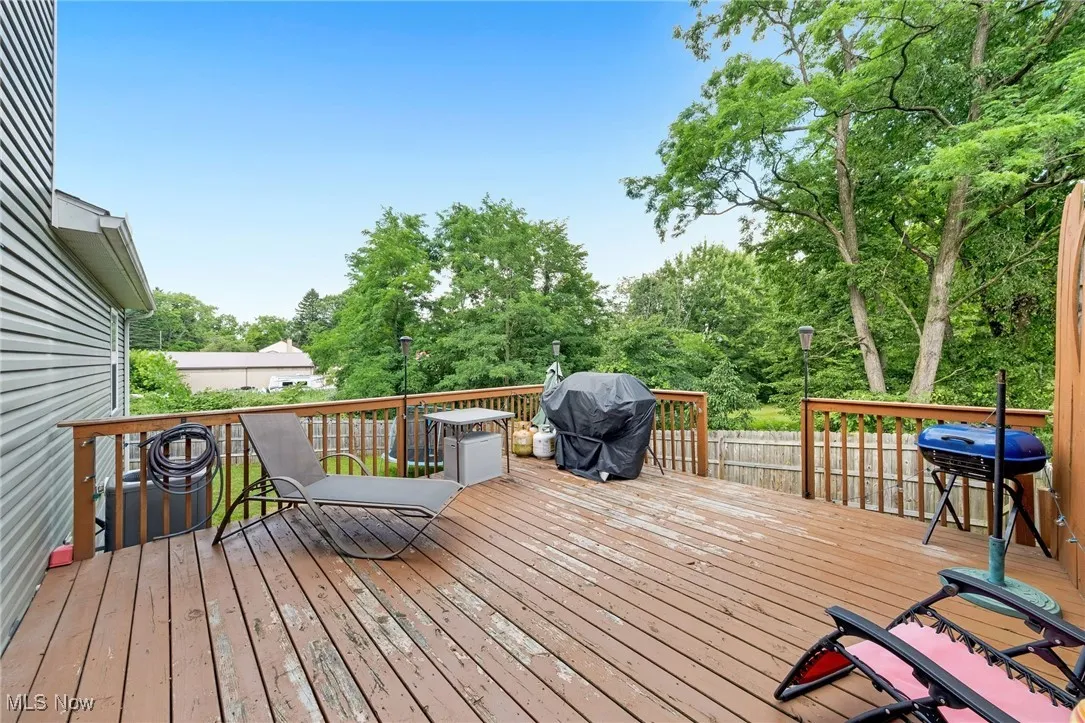 Wooden terrace featuring grilling area and view of scattered trees