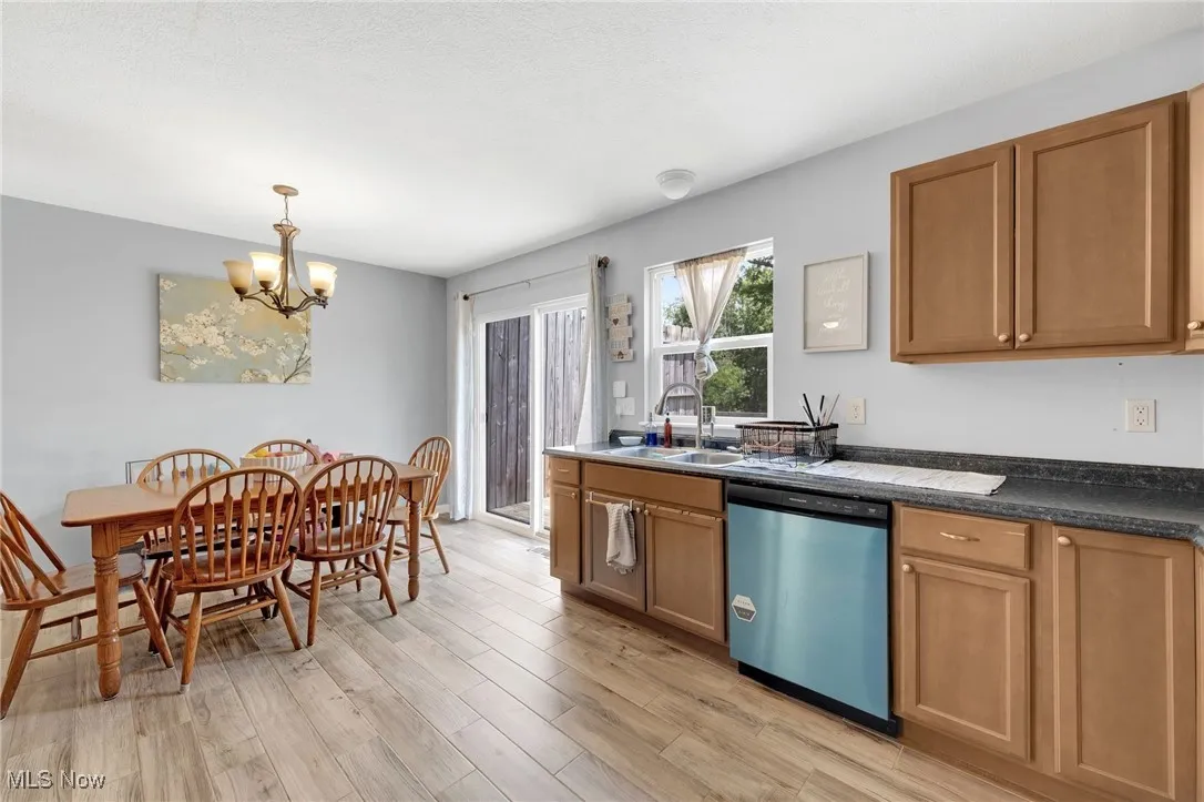 Kitchen featuring dishwasher, a chandelier, brown cabinetry, and light wood finished floors