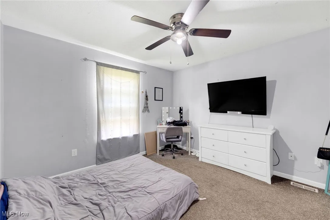 Bedroom with carpet flooring, a ceiling fan, and an office area