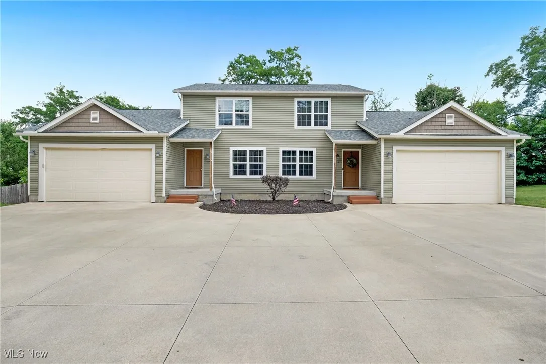 Traditional home with driveway, a garage, and roof with shingles