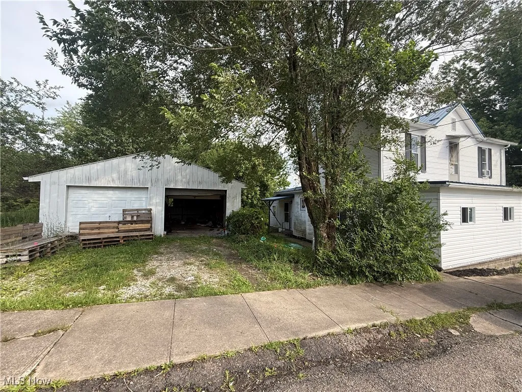View of property exterior with a detached garage and an outbuilding
