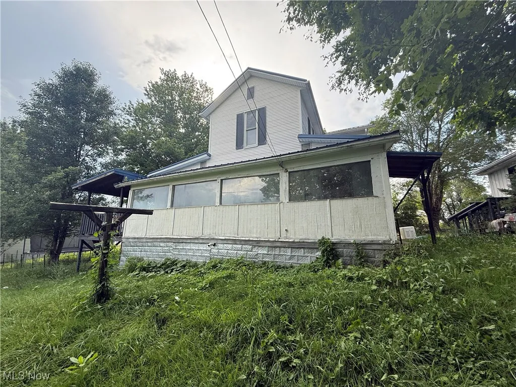 View of side of property with a sunroom and a metal roof